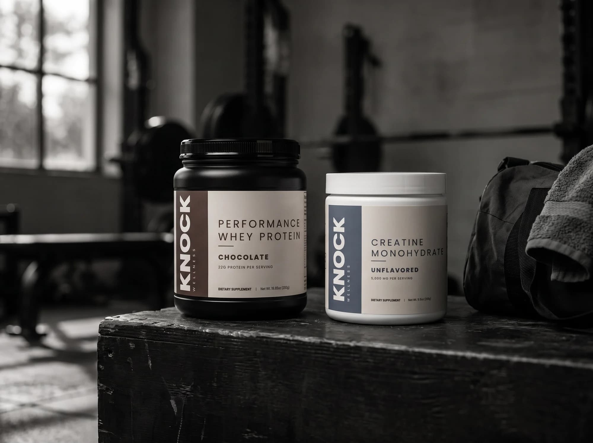 KNOCK Whey Protein and Creatine Monohydrate on a gym bench